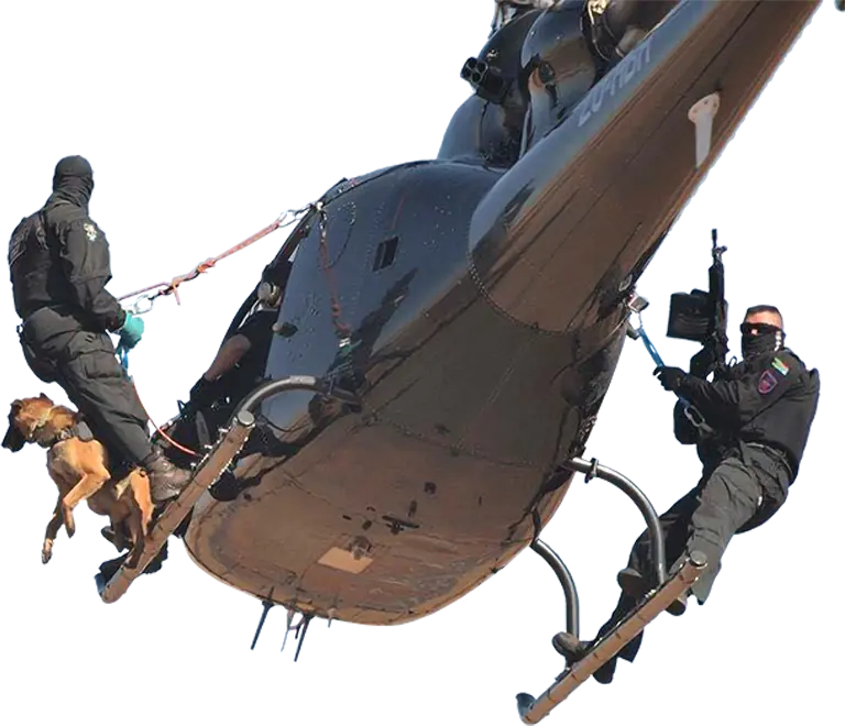 An SRU K9 handler with his dog and an armed officer on the skids of a helicopter in flight
